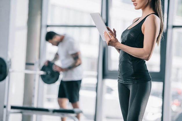 Personal trainer using iPad device to help instruct student with fitness lessons